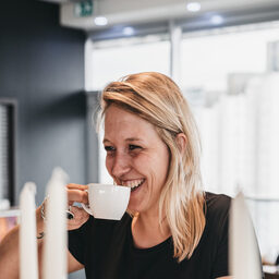 A woman drinking coffee in a coffee shop.