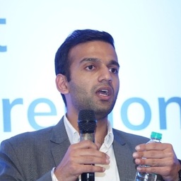 A man in a suit speaking into a microphone.