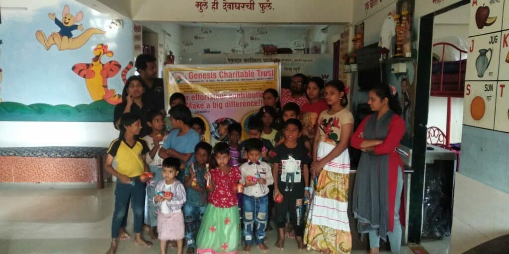 Group of children and adults holding a banner inside a classroom decorated with children's drawings and educational charts.