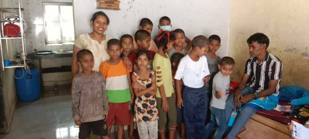 A group of children and two adults standing in a room, smiling at the camera.