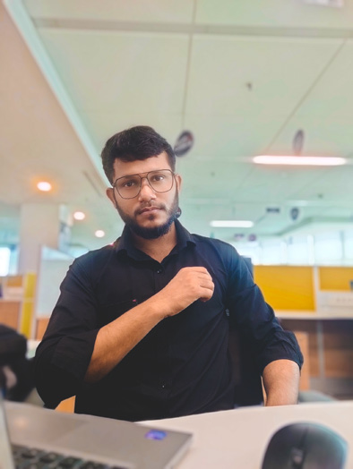 A man sitting at a desk with a laptop in front of him.