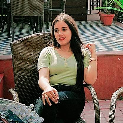 A woman in a green shirt sitting on a wicker chair.