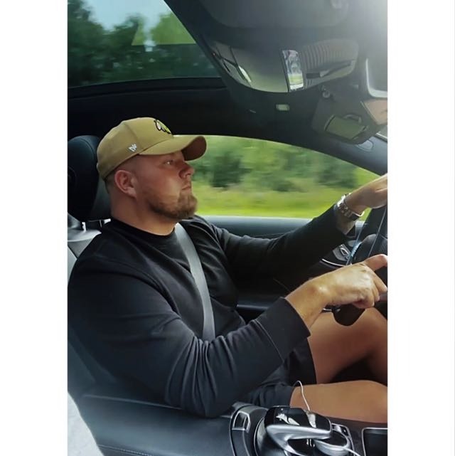 A man driving a car with a hat on his head.